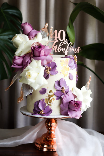 Single tier white buttercream cake with purple and white sugar roses and gold leaf