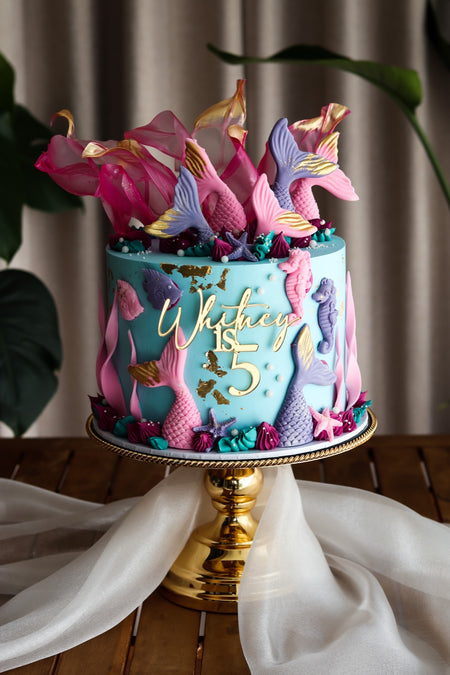 Teal mermaid themed birthday cake with sugar mermaid tails, seahorses and coral