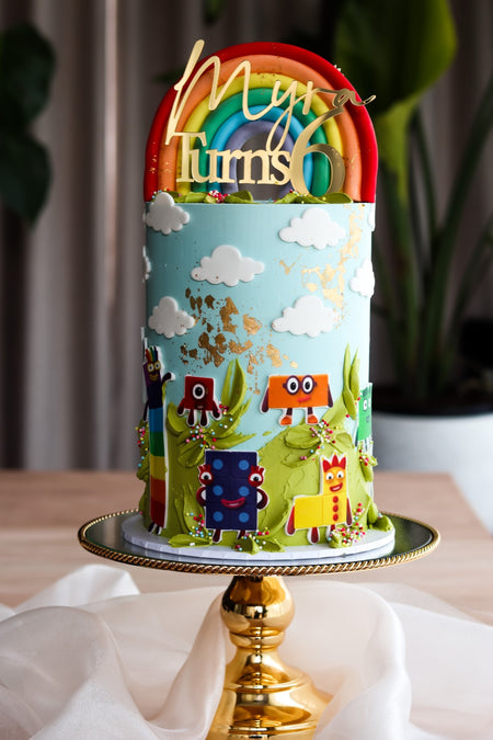 Colourful number themed birthday cake with a fondant rainbow and clouds