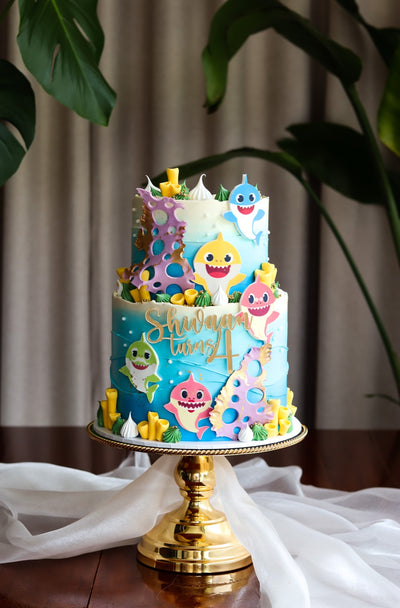Two tier blue ocean themed birthday cake with fondant sharks and coral