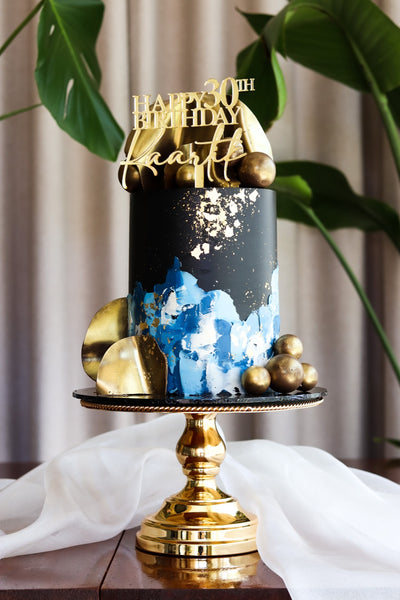 Single tier navy blue and gold abstract cake with gold spheres and gold leaf