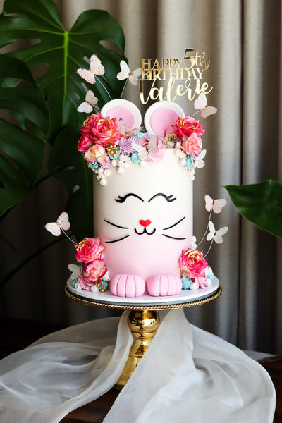Single tier pink kitten character birthday cake with a sugar flower crown and butterflies