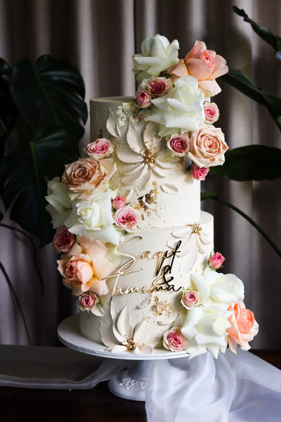 Two tier textured ivory wedding cake with blush and peach sugar roses