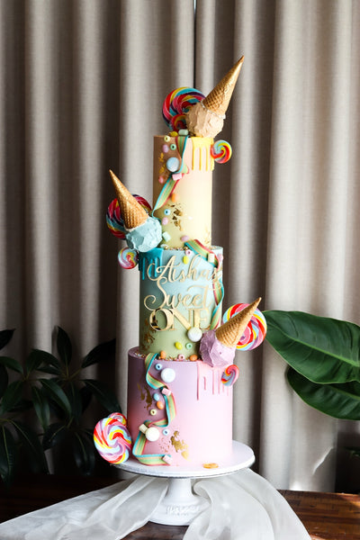 Three tier ice cream themed birthday cake with waffle cones, lollipops and sprinkles