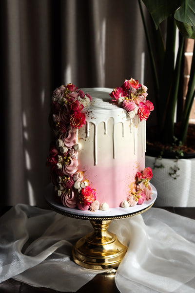 Single tier pink ombre drip cake with piped buttercream florals and gold detail