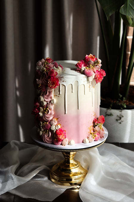 Pink ombre drip cake with piped buttercream florals and gold detail