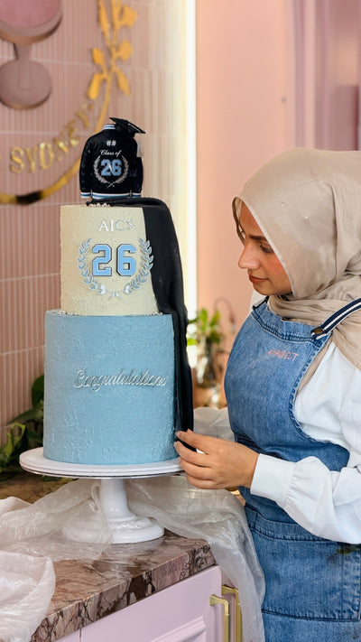 Two-tier graduation cake with a Class of 26 jacket topper